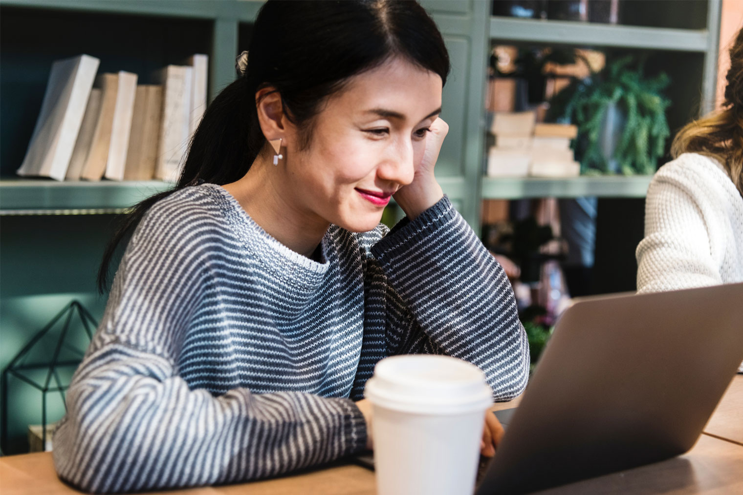 Kvinne som smiler og arbeider på en laptop